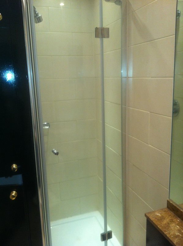 Frameless glass shower enclosure with chrome fittings in East Sheen